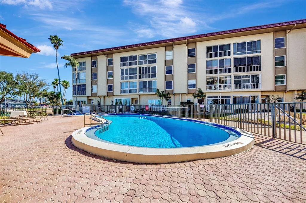 An aerial view of a swimming pool, hot tub, and shuffleboard court near a canal — 113 ISLAND WAY UNIT 241, CLEARWATER BEACH, FL