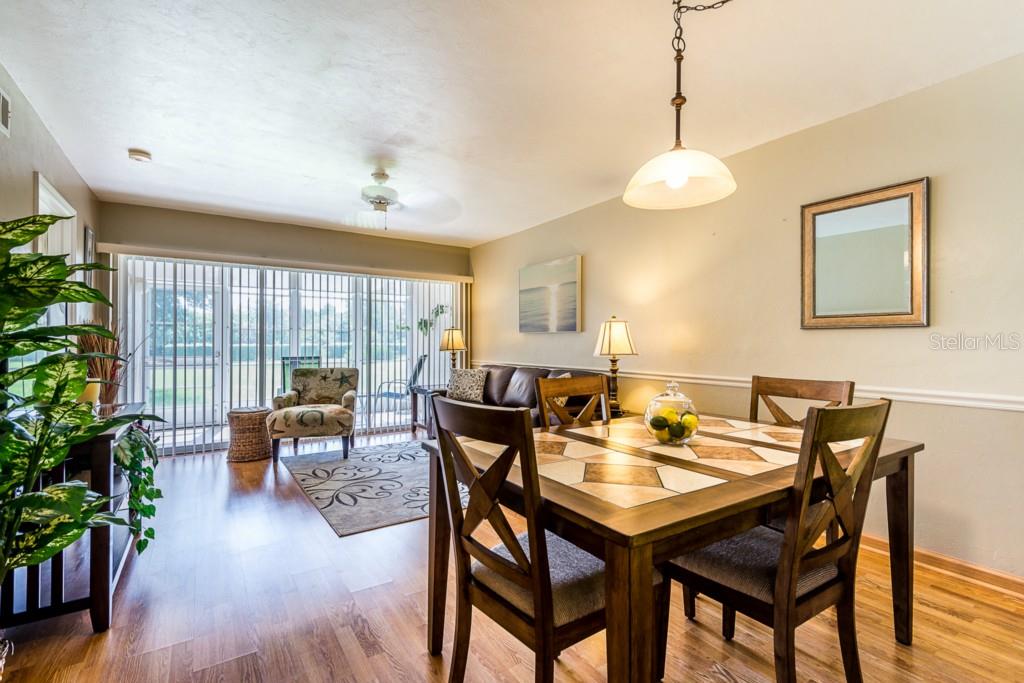 A dining area with a tiled table and chairs opens into a living room with sliding doors — 11644 EGRET CIRCLE UNIT 1101, LAKE SUZY, FL