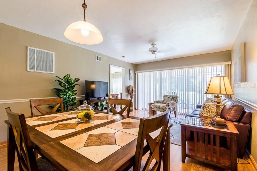 A dining area with a tiled table opens into a living room with a leather sofa — 11644 EGRET CIRCLE UNIT 1101, LAKE SUZY, FL