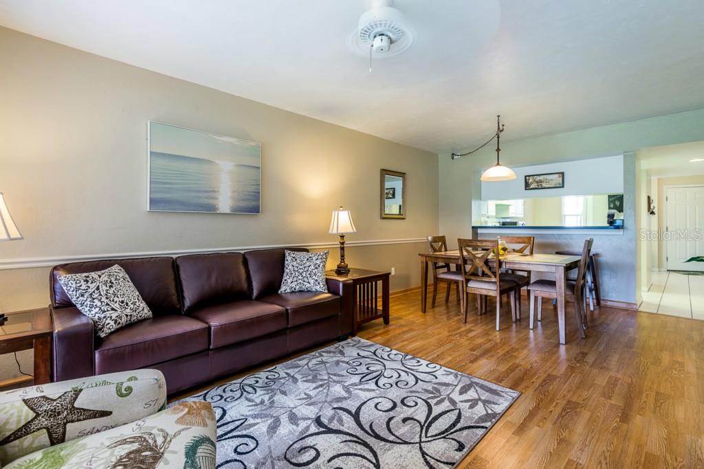 A living room with a brown leather sofa, dining area, and hardwood floors — 11644 EGRET CIRCLE UNIT 1101, LAKE SUZY, FL