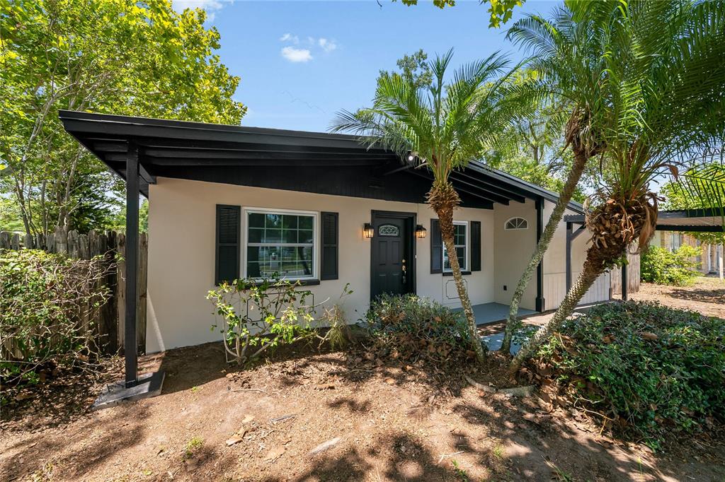 A single-story house with a black roof, tan exterior, and palm trees in the front yard — 7402 WISHING WELL COURT, TAMPA, FL