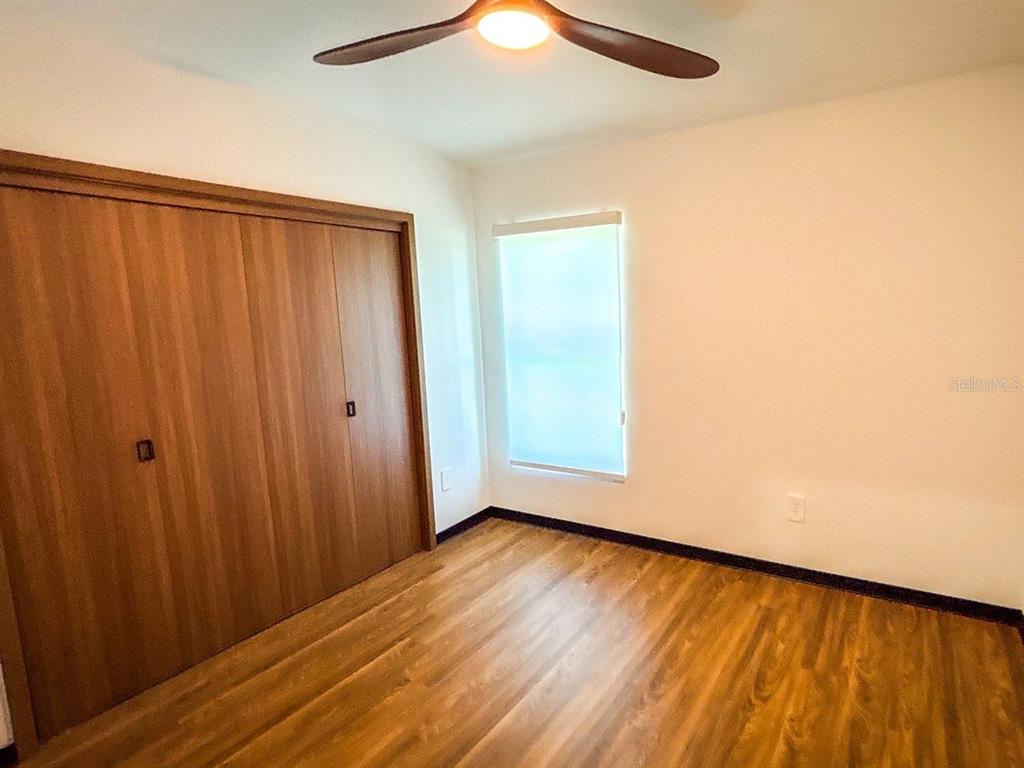 A bedroom features wood-look flooring, a large closet with sliding doors, and a ceiling fan — 344 VIREO AVENUE, SEBRING, FL