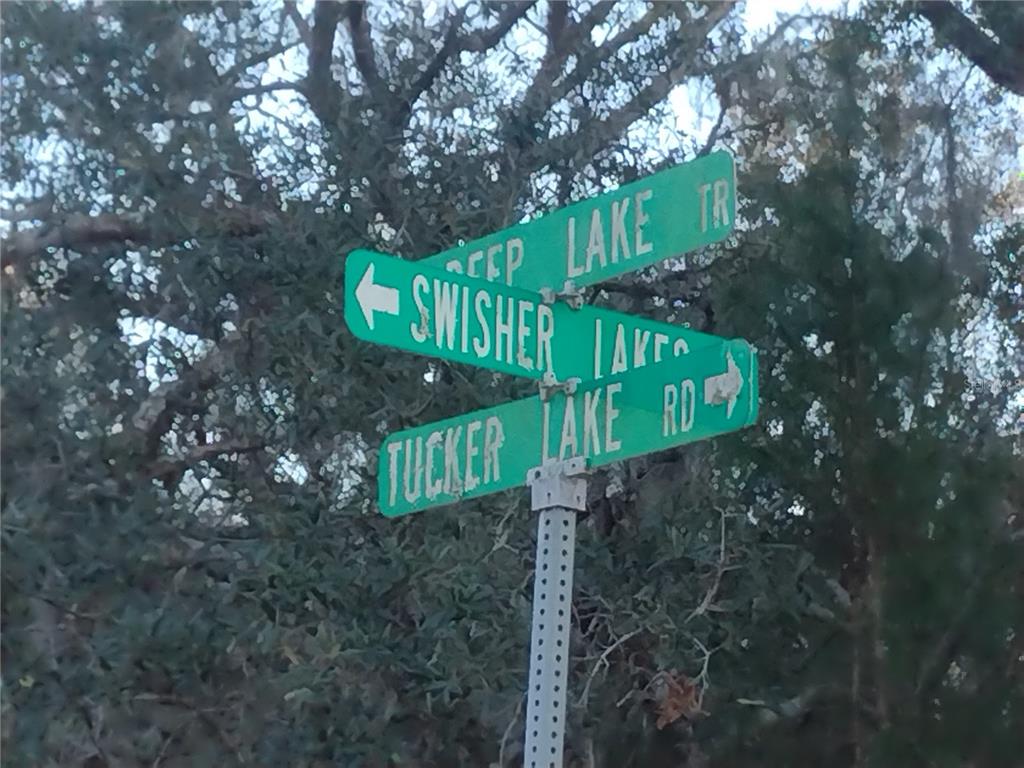 A street sign post displays the names Swisher Lake and Tucker Lake Road — 89 TUCKER LAKE ROAD, MELROSE, FL