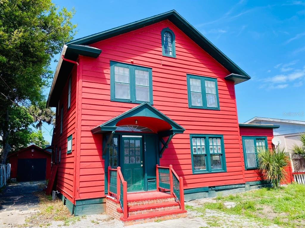 A two-story house with red horizontal siding, green trim, and a small front porch — 415 BRADDOCK AVENUE, DAYTONA BEACH, FL