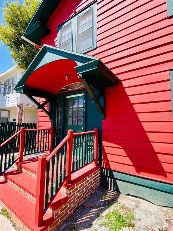 A red house with green trim features a covered front porch and brick steps — 415 BRADDOCK AVENUE, DAYTONA BEACH, FL