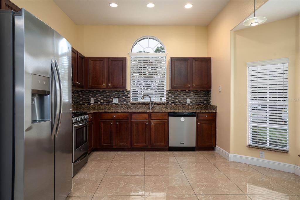 A single-story house with a tan stucco exterior, a two-car garage, and a front lawn — 3078 VERBENA DRIVE, DELTONA, FL