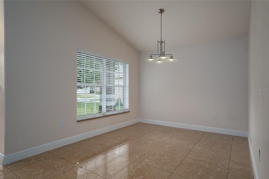 A covered entryway features a front door, two windows with blinds, and concrete flooring — 3078 VERBENA DRIVE, DELTONA, FL