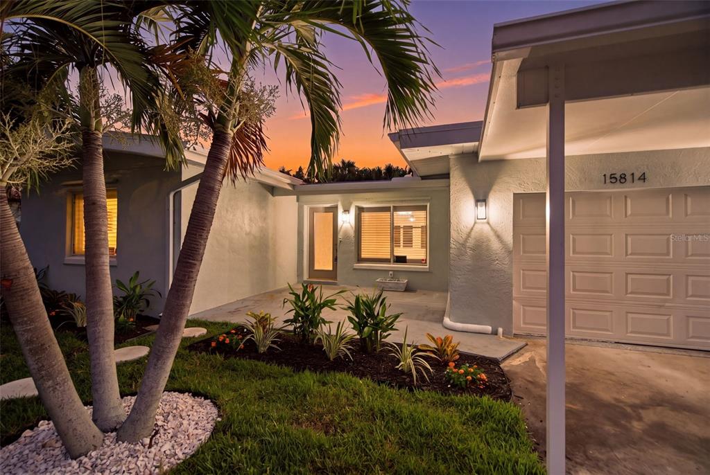 A single-story house exterior features a palm tree, a front porch, and a garage — 15814 3RD STREET E, REDINGTON BEACH, FL