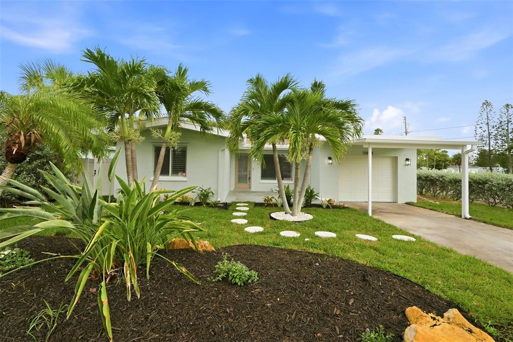 A single-story house with a carport, palm trees, and a landscaped front yard — 15814 3RD STREET E, REDINGTON BEACH, FL