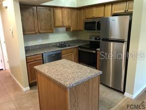 A kitchen with wood cabinets, stainless steel appliances, and a central island with stone countertops — 248 TIMBERLINE TRAIL, ORMOND BEACH, FL