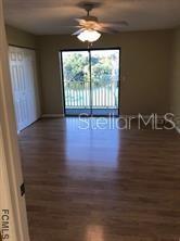 An empty room with wood-look flooring, a ceiling fan, and sliding glass doors to a balcony — 248 TIMBERLINE TRAIL, ORMOND BEACH, FL