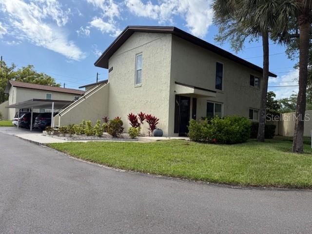 A two-story stucco apartment building features an exterior staircase and a covered parking area — 501 E BAY DRIVE UNIT 104, LARGO, FL