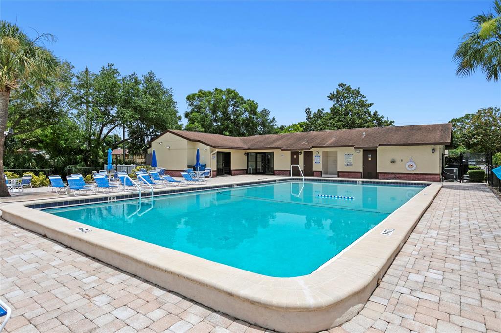 An outdoor swimming pool with lounge chairs on a paved deck next to a building — 501 E BAY DRIVE UNIT 104, LARGO, FL