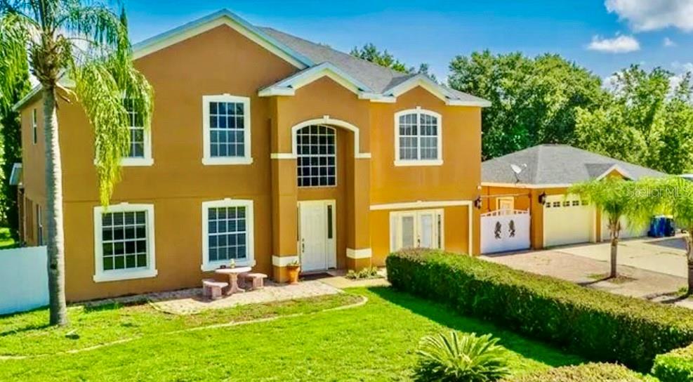 A two-story tan house with a detached garage and a front yard — 13315 DAFFODIL WAY, ASTATULA, FL