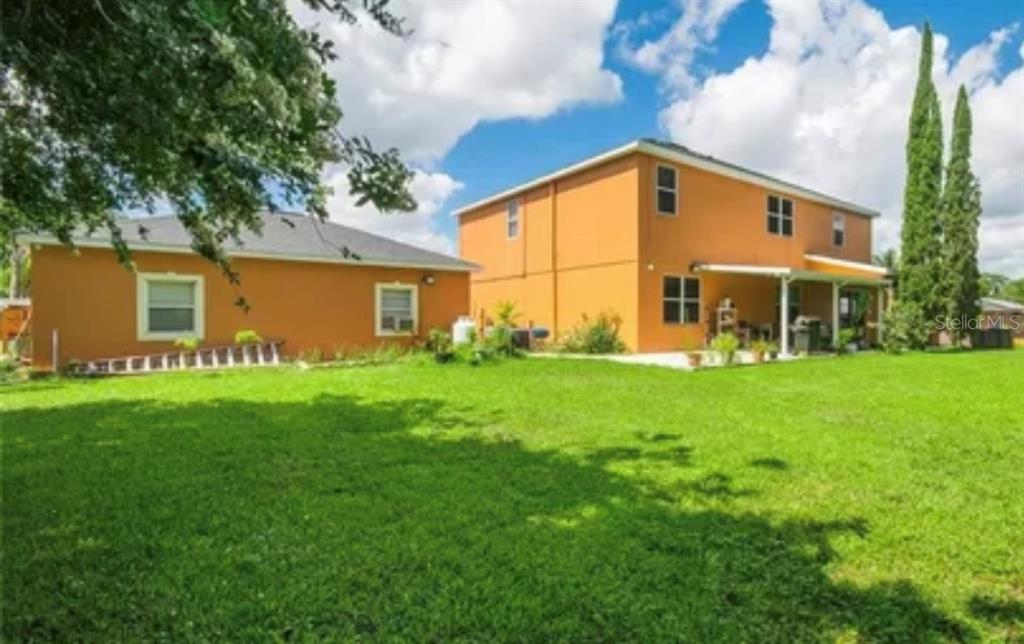 A two-story orange house with a large backyard and a smaller attached structure — 13315 DAFFODIL WAY, ASTATULA, FL