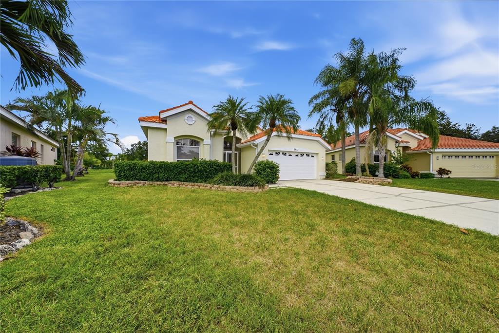A single-story house with a white garage, tiled roof, and palm trees in the front yard — 6817 SUPERIOR STREET CIRCLE, SARASOTA, FL