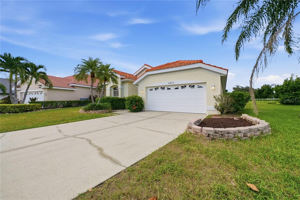 A single-story house with a white garage, a concrete driveway, and palm trees in Florida — 6817 SUPERIOR STREET CIRCLE, SARASOTA, FL