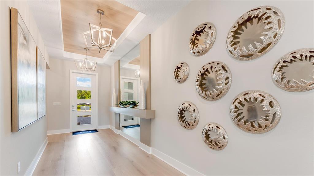 A bright entryway features light wood flooring, a coffered ceiling, and decorative wall mirrors — 1246 CRESSWIND BOULEVARD, DELAND, FL