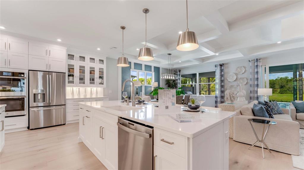A modern white kitchen with a large island, stainless steel appliances, and an adjacent living area — 1246 CRESSWIND BOULEVARD, DELAND, FL