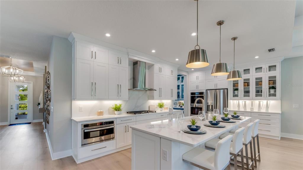 A modern white kitchen features a large island, stainless steel appliances, and pendant lighting — 1246 CRESSWIND BOULEVARD, DELAND, FL