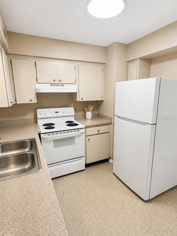 A kitchen features beige cabinets, white appliances, a double sink, and light-colored countertops — 5222 BOGDONOFF DRIVE, SEFFNER, FL