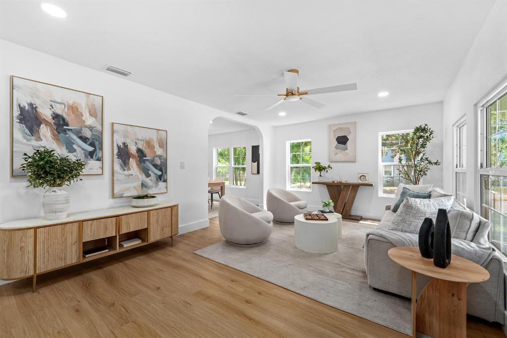 A bright living room features light wood floors, two cream armchairs, and a gray sofa — 1230 E HENRY AVENUE, TAMPA, FL