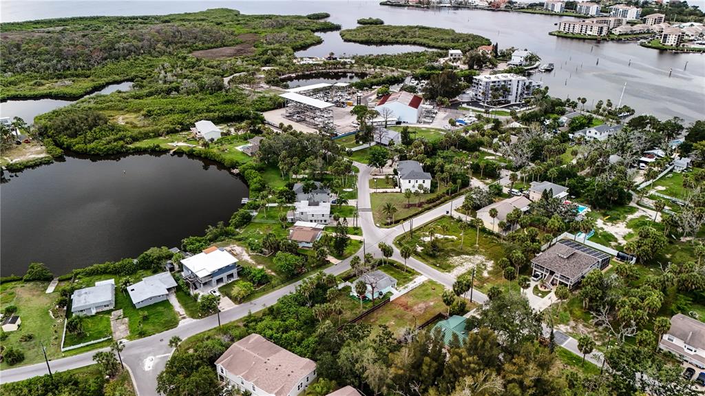 An aerial view shows a residential neighborhood with houses, palm trees, and a nearby marina — 4846 LIMESTONE DRIVE, PORT RICHEY, FL