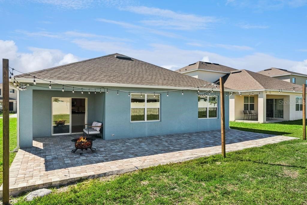 A light blue house features a paved patio with a fire pit and string lights — 5235 MAHOGANY DRIVE, MOUNT DORA, FL
