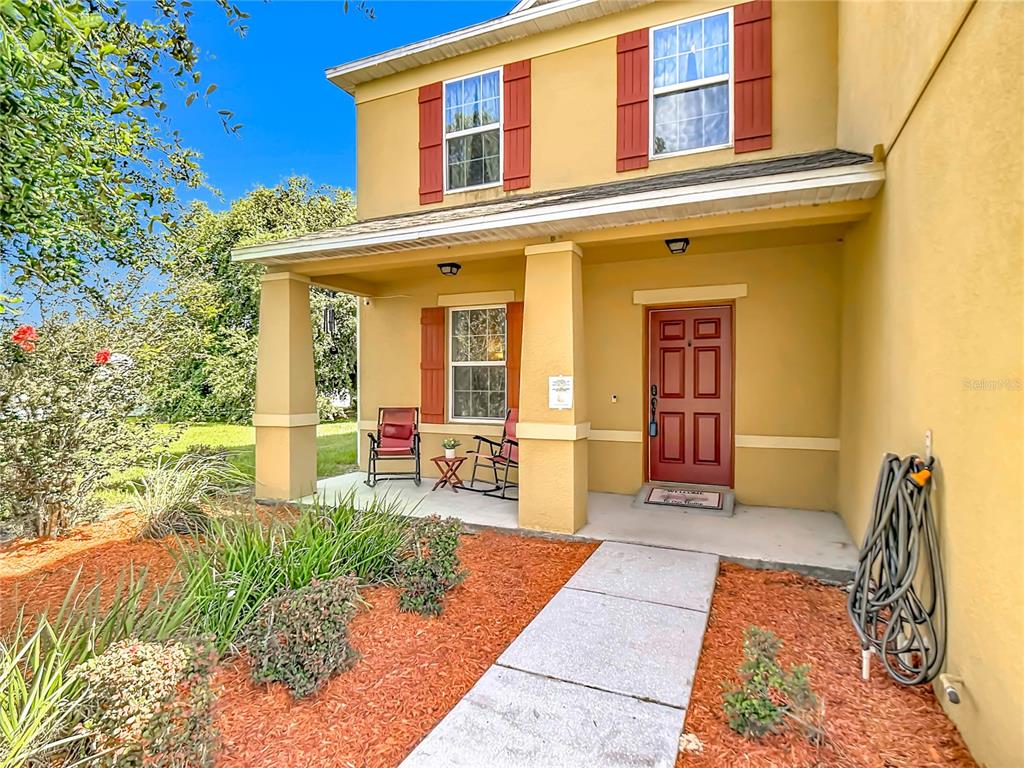 A two-story house exterior features a covered front porch, red shutters, and a red door — 205 TIFTON STREET, WINTER HAVEN, FL