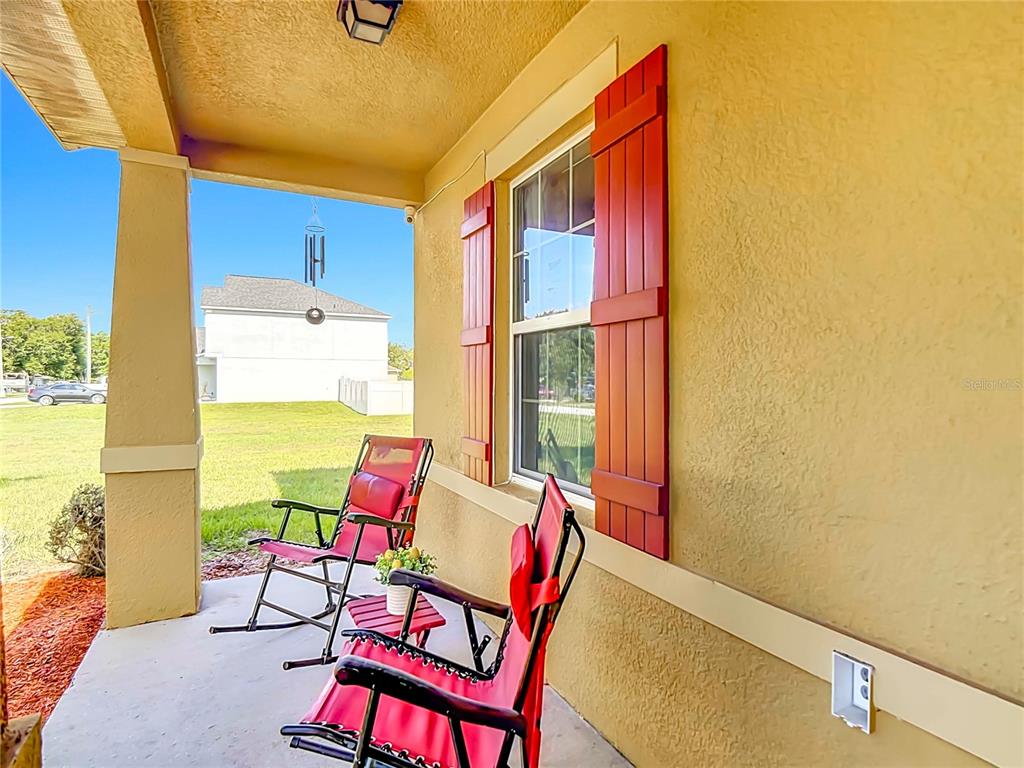 A covered front porch features two red chairs, a small table, and red window shutters — 205 TIFTON STREET, WINTER HAVEN, FL