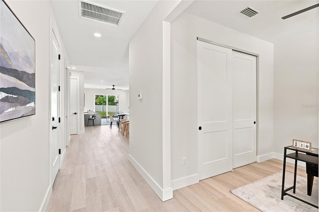 A hallway with light wood flooring leads to an open living area with a sliding door — 2139 20TH AVENUE SW, LARGO, FL