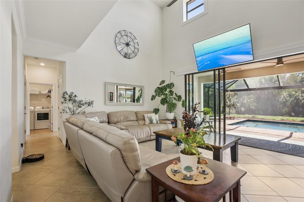 A living room with a sectional sofa, high ceilings, and a view of a pool — 20604 BENISSIMO DRIVE, VENICE, FL