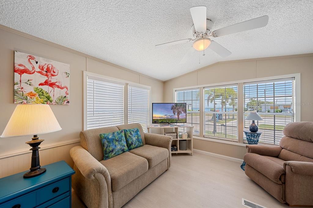 A single-story manufactured home with tan siding, orange shutters, and a brick paver patio — 58 MONTEGO DRIVE, PALMETTO, FL