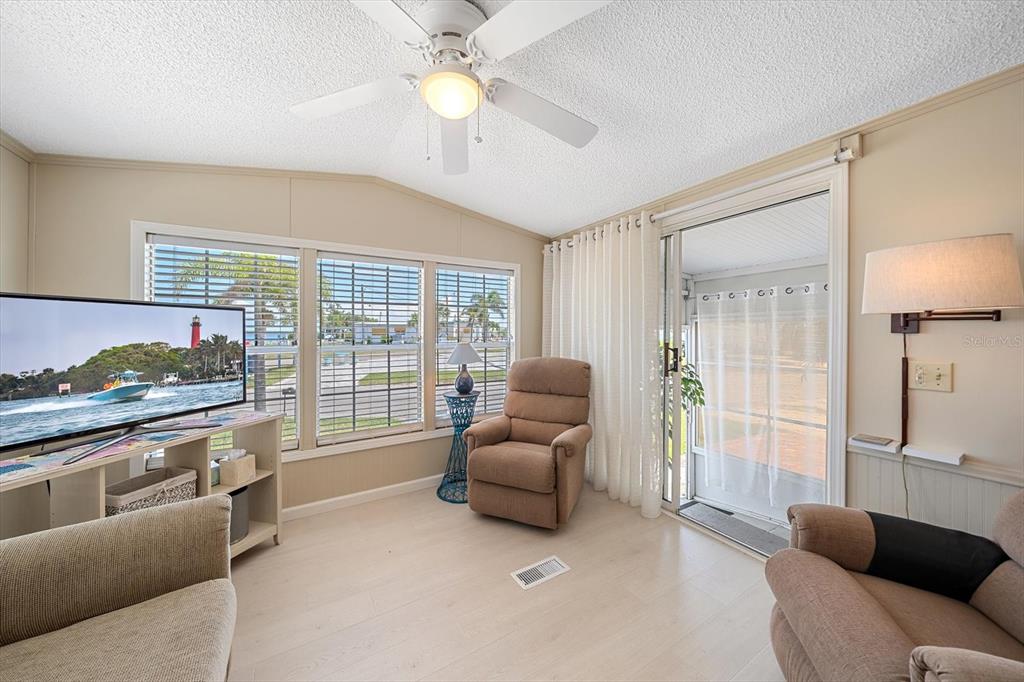 A living room features a beige sofa, a recliner, a ceiling fan, and large windows — 58 MONTEGO DRIVE, PALMETTO, FL