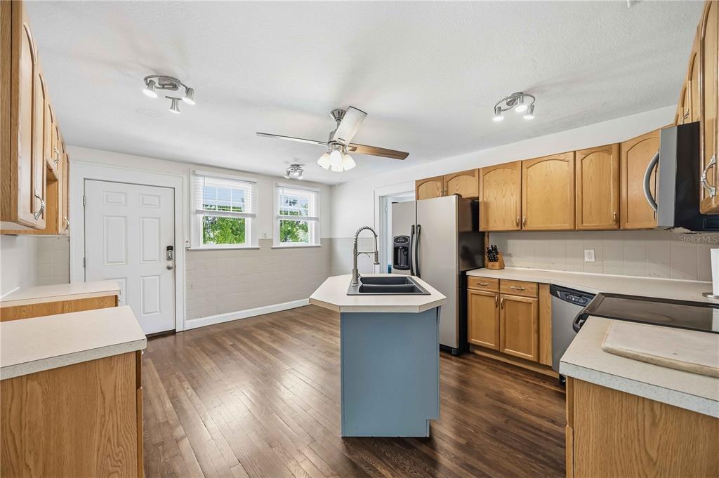 A kitchen features wood cabinets, stainless steel appliances, a blue island, and wood-look flooring — 815 SOLONA LOOP, PUNTA GORDA, FL