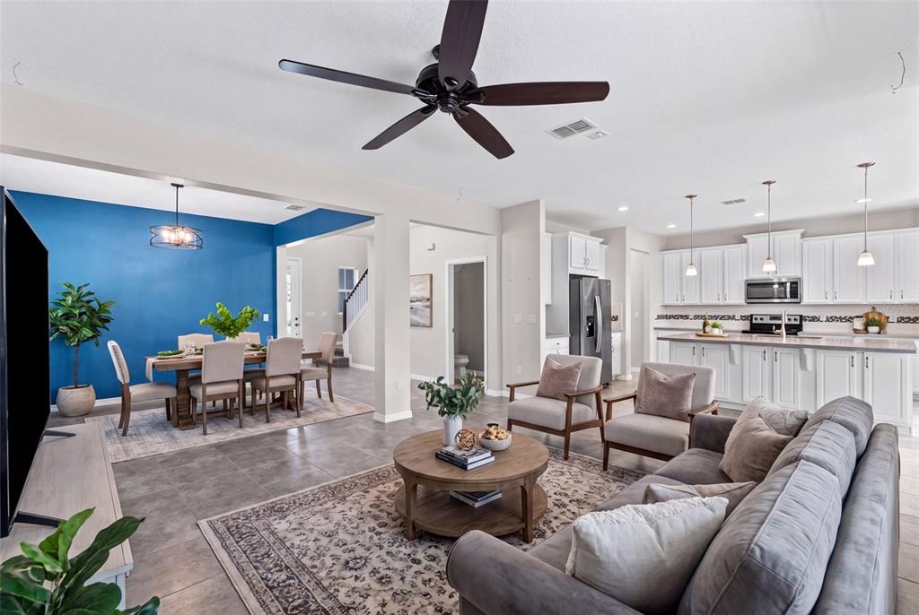 An open-concept living area features gray tile flooring, a ceiling fan, and a blue-walled dining space — 2819 STONEGATE DRIVE, OCOEE, FL