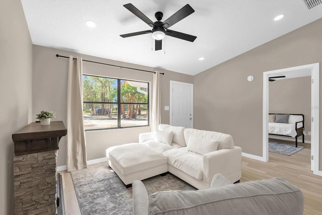 A living room features a white sectional sofa, a stone fireplace, and a ceiling fan — 4840 MANGO AVENUE, COCOA, FL