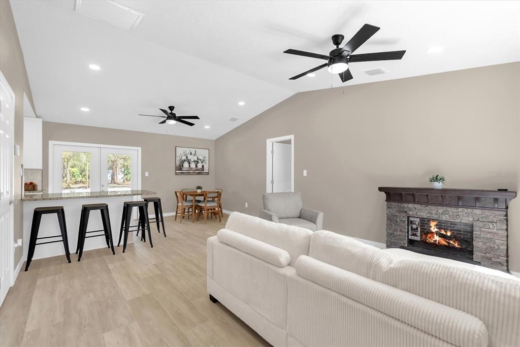 A living room features a stone fireplace, white sofa, kitchen island with stools, and dining area — 4840 MANGO AVENUE, COCOA, FL