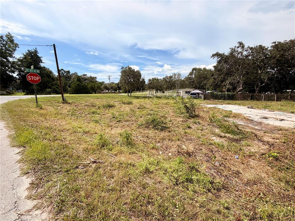 A vacant, grassy lot features a stop sign and a concrete slab foundation — 18351 SE 20TH PLACE, SILVER SPRINGS, FL