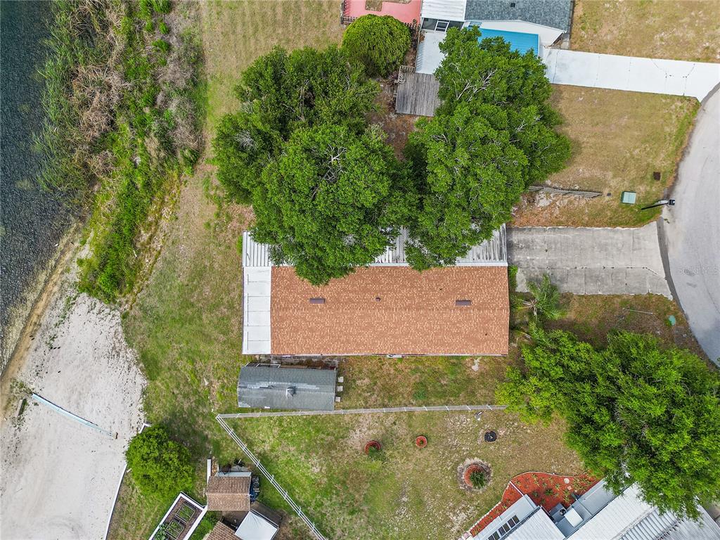 An aerial view shows a house with a brown roof situated between trees and water — 1025 CARVER STREET, LAKE WALES, FL