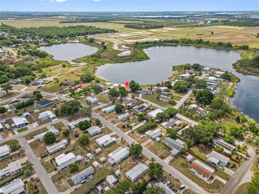 An aerial view shows a residential neighborhood with many mobile homes situated near a lake — 1025 CARVER STREET, LAKE WALES, FL