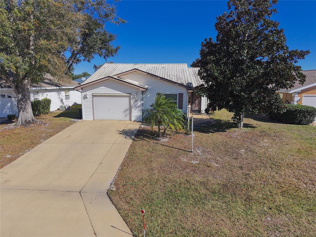 A single-story house with a metal roof, a one-car garage, and a concrete driveway — 1626 WILLOW RUN, SEBRING, FL