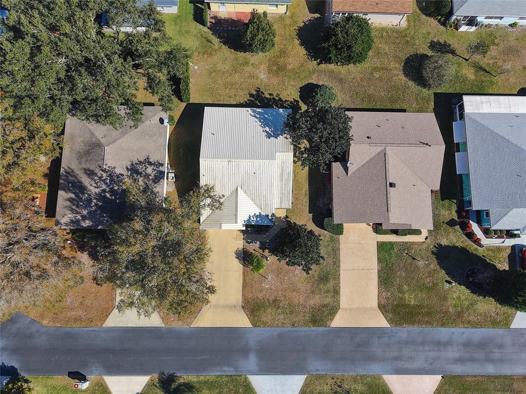 An aerial view shows three suburban houses with driveways and lawns along a paved street — 1626 WILLOW RUN, SEBRING, FL