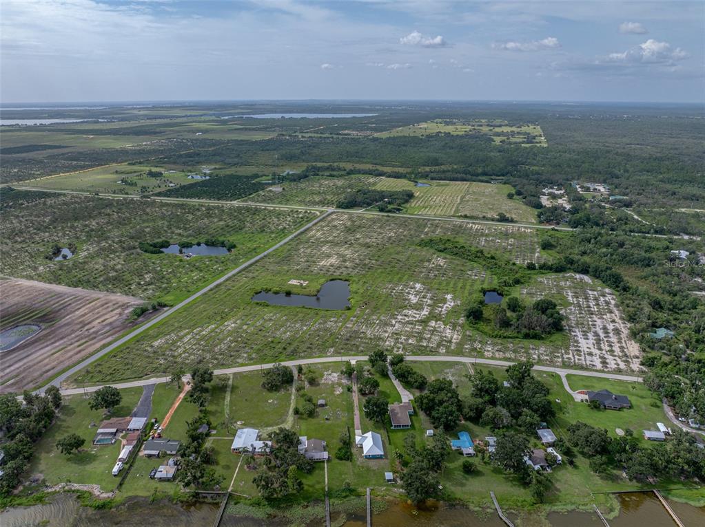 An aerial view shows a rural landscape with scattered houses, ponds, and large open fields — 0 LAKE REEDY BOULEVARD, FROSTPROOF, FL