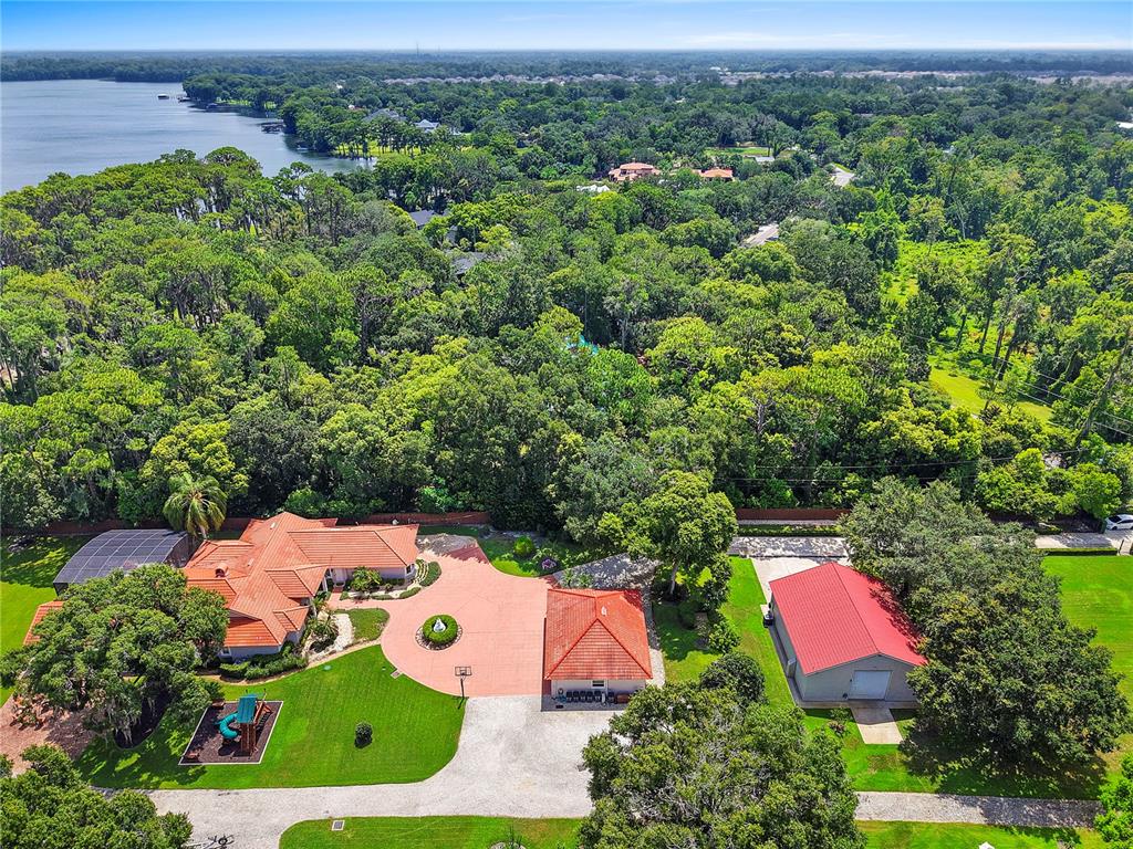 An aerial view shows a house with a red tile roof, a detached garage, and a playground — 2622 LAKE HOWELL LANE, WINTER PARK, FL