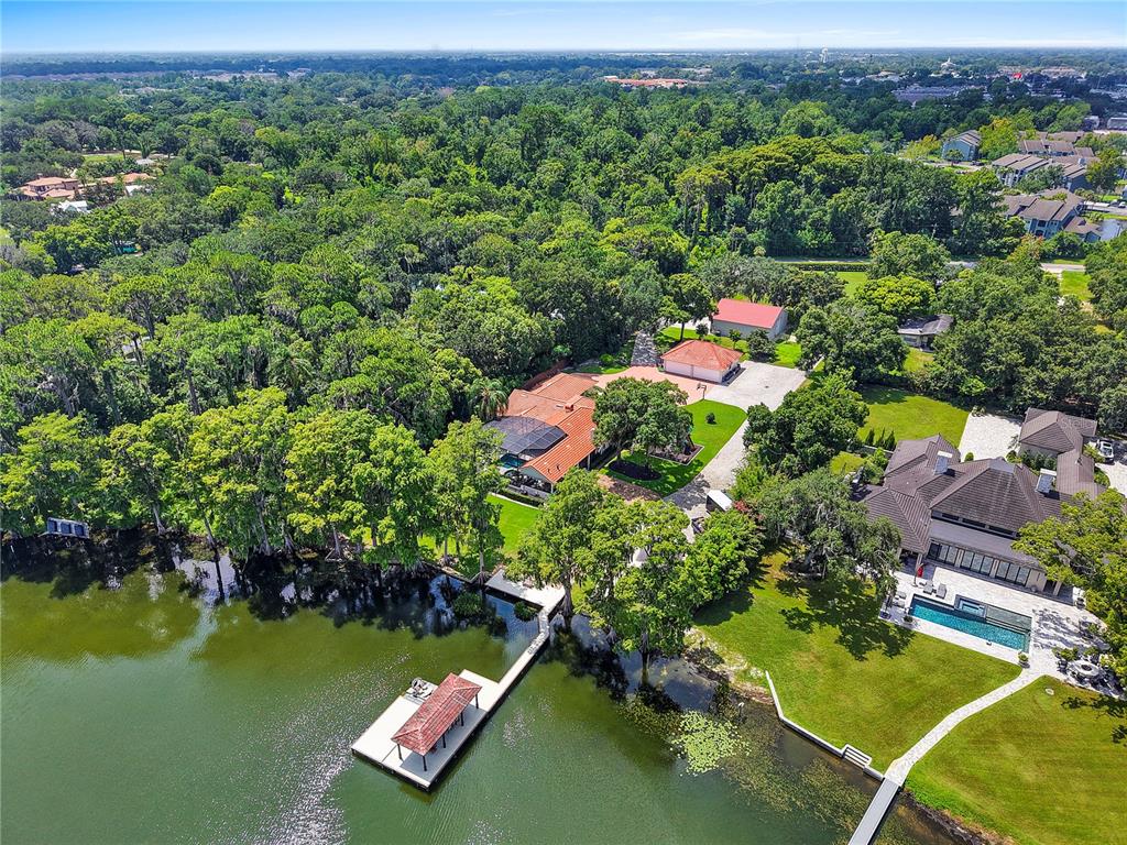An aerial view shows two waterfront houses with docks, pools, and lush trees — 2622 LAKE HOWELL LANE, WINTER PARK, FL