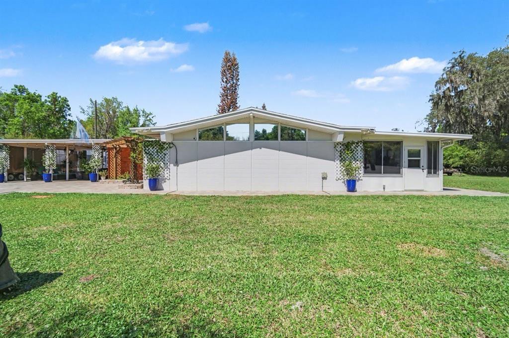 A single-story house with a gabled roof, white exterior walls, and a large grassy yard — 2207 POINSETTIA LANE, DELAND, FL