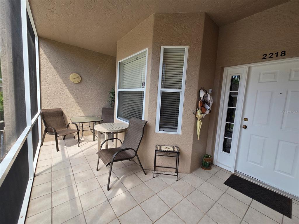 A screened-in patio features tiled flooring, outdoor furniture, and a white front door — 5320 HYLAND HILLS AVENUE UNIT 2218, SARASOTA, FL