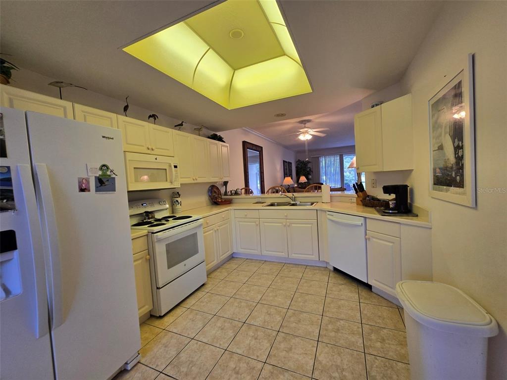 A kitchen with white cabinets, white appliances, tile flooring, and a recessed ceiling light — 5320 HYLAND HILLS AVENUE UNIT 2218, SARASOTA, FL