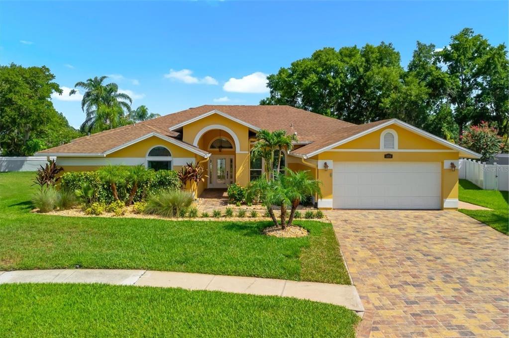An aerial view of a yellow single-story house with a brown roof and paver driveway — 1874 STABLE TRAIL, PALM HARBOR, FL
